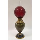 An oil lamp, with acid etched cranberry shade, the Doulton style stoneware body with brass mounts,