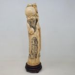 An early 20th century Chinese ivory tusk, carved in the form of Shou Lao, on wooden base, 38 cm
