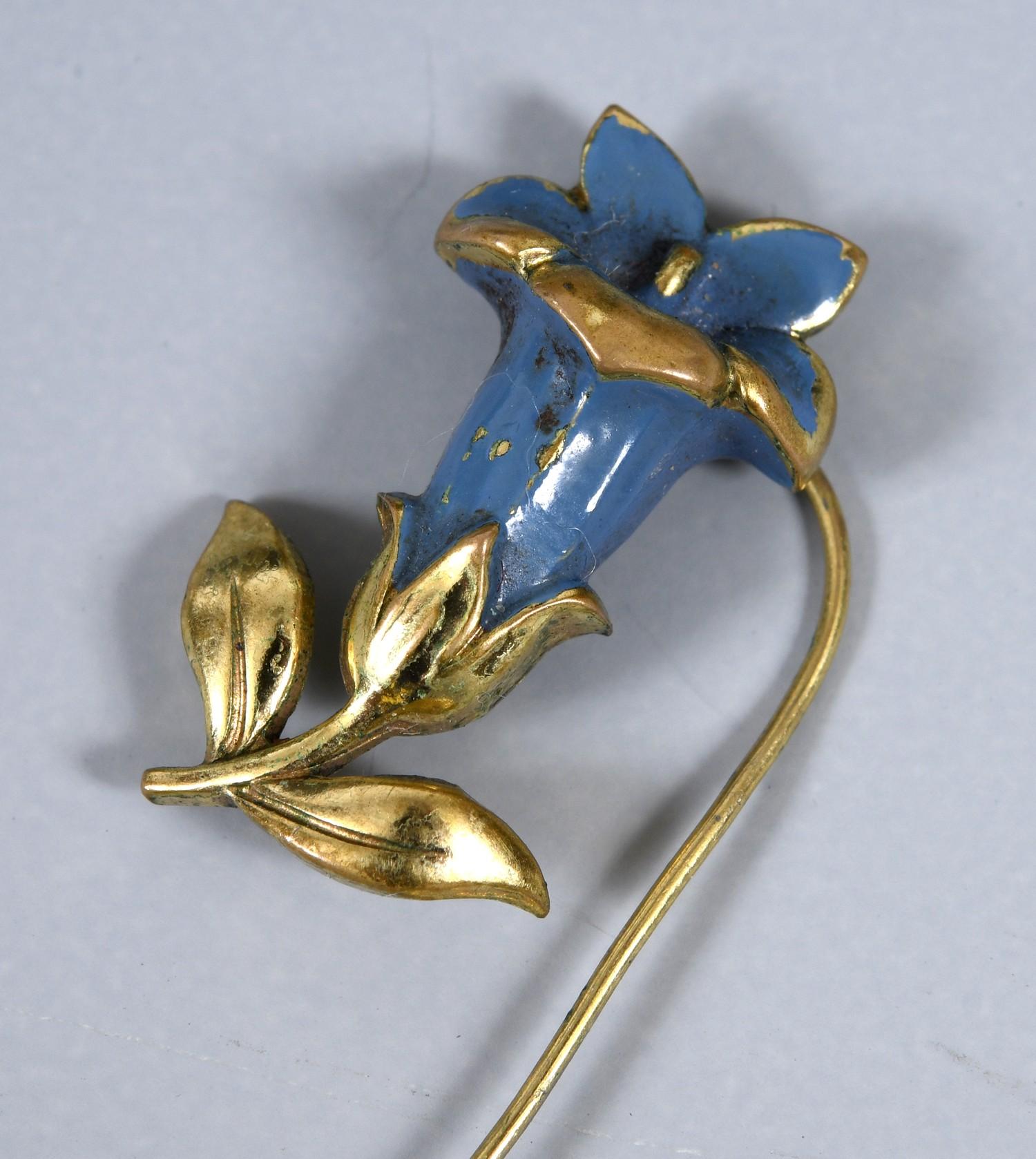 An Art Nouveau yellow metal and enamel pin, in the form of a flower