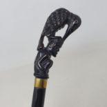 A walking stick, the carved horn handle in the form of a bird atop a crouching man, on ebonised