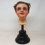A 19th century wax head, with glass eyes, on an ebonised stand, 40 cm high