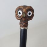 A walking stick, the wooden handle carved in the form of an owl, with glass eyes, on ebonised shaft,