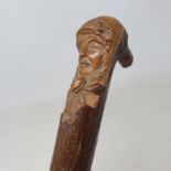 A folk art walking stick, the carved handle in the form of a female head, the shaft carved a dog, 92