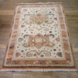 A cream ground rug, main peach border, centre with pair or geometric medallions, 226 x 168 cm