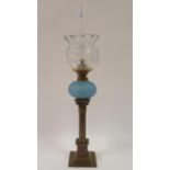 An oil lamp, with clear acid etched shade, opaque blue glass well, on brass Corinthian column form