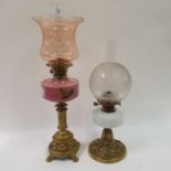 An oil lamp, with peach glass shade, with pink glass well, on brass base, 69 cm, and an oil lamp,