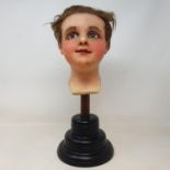 A 19th century wax head, with glass eyes, on an ebonised stand, 40 cm high Unable to give shipping