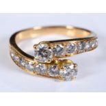 A yellow coloured metal crossover ring, set two rows of seven graduated diamonds, approx. ring