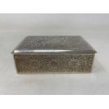 A Persian silver coloured metal table cigarette box, decorated flowers and foliage, 13.5 cm wide