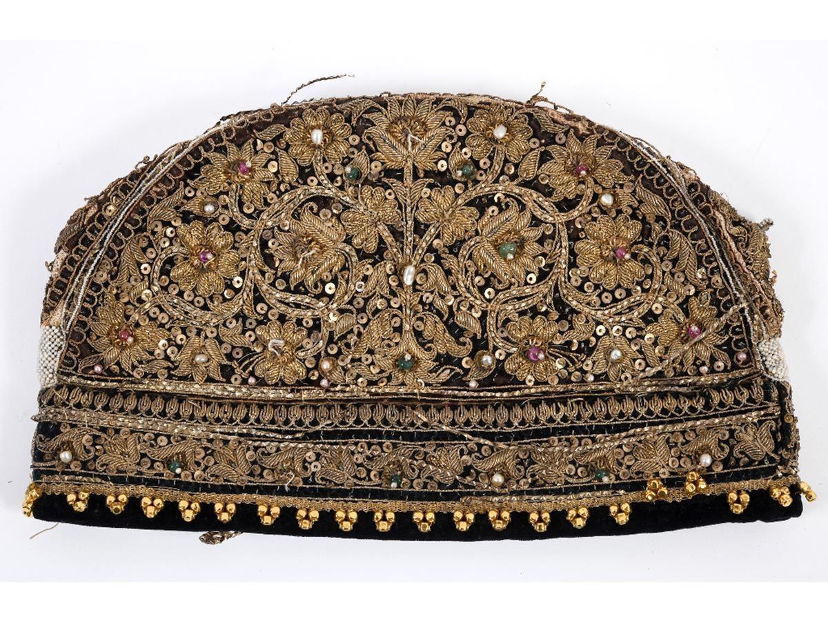 An Indian velvet cap, with gold thread decoration applied gems, 27.5 cm wide See illustration