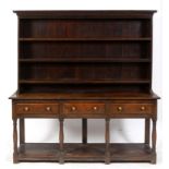 An oak dresser, the dentil cornice above a three tier plate rack, the base with three frieze drawers