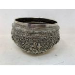 A Burmese style silver coloured metal bowl, embossed figures and foliage, dented and holed, 13 cm