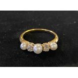 A yellow coloured metal ring, set three seed pearls and two diamond chips, approx. ring size O