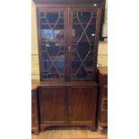 A late 19th century mahogany bookcase on cupboard, having a pair of astragal bar glazed doors