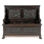 An oak box settle, carved flowers, foliage, ribbon ties and swags, 121 cm wide