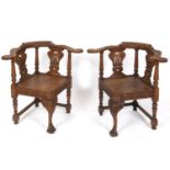 A pair of oak corner armchairs, carved flowers and foliage, on cabriole front legs, with claw and