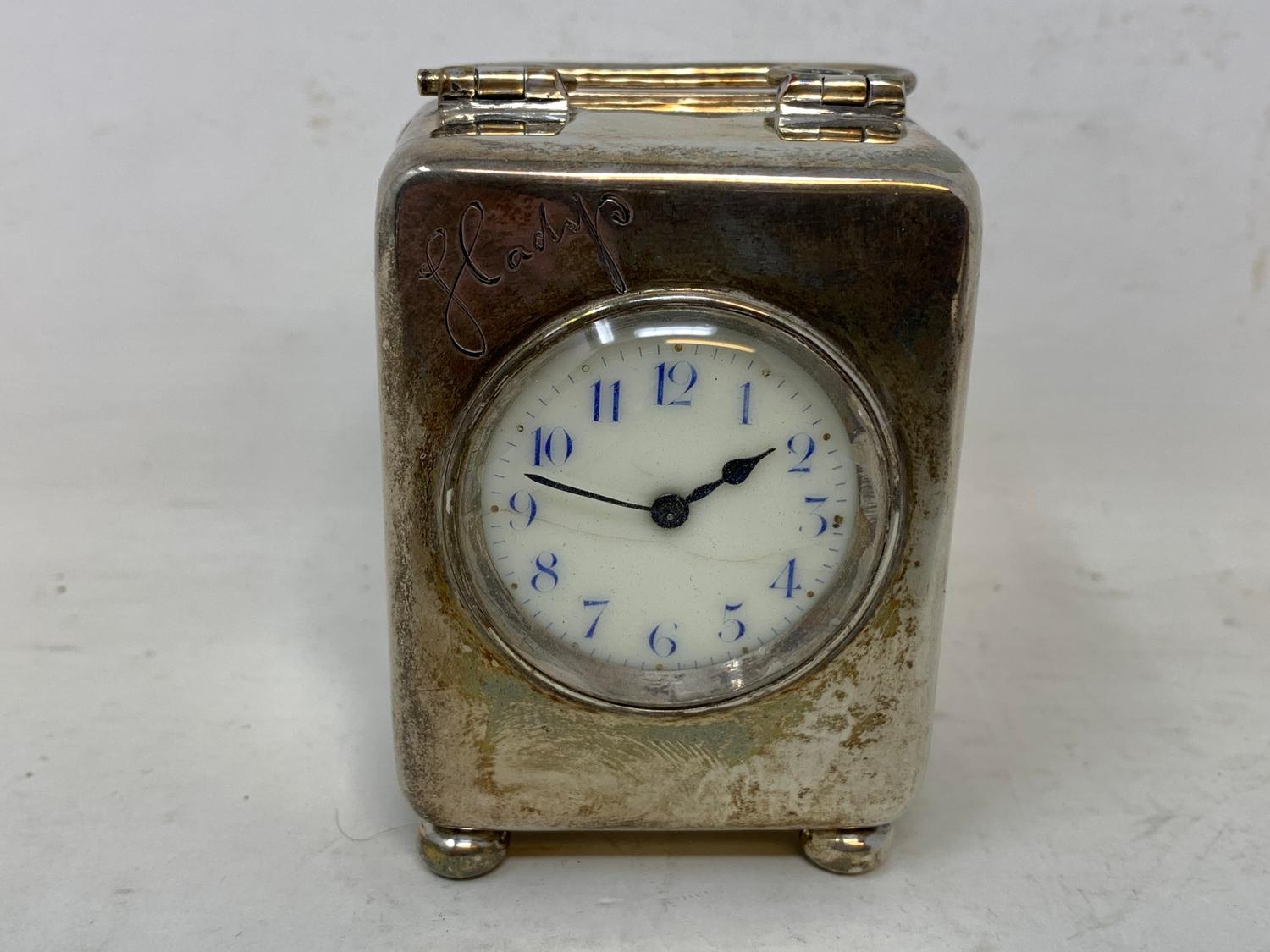 An Edward VII travelling clock, the 3.5 cm dial with Arabic numerals, in a silver case, inscribed