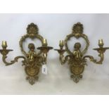 A pair of gilt brass two light wall lamps, decorated putti and shells, 34 cm high (2) Good