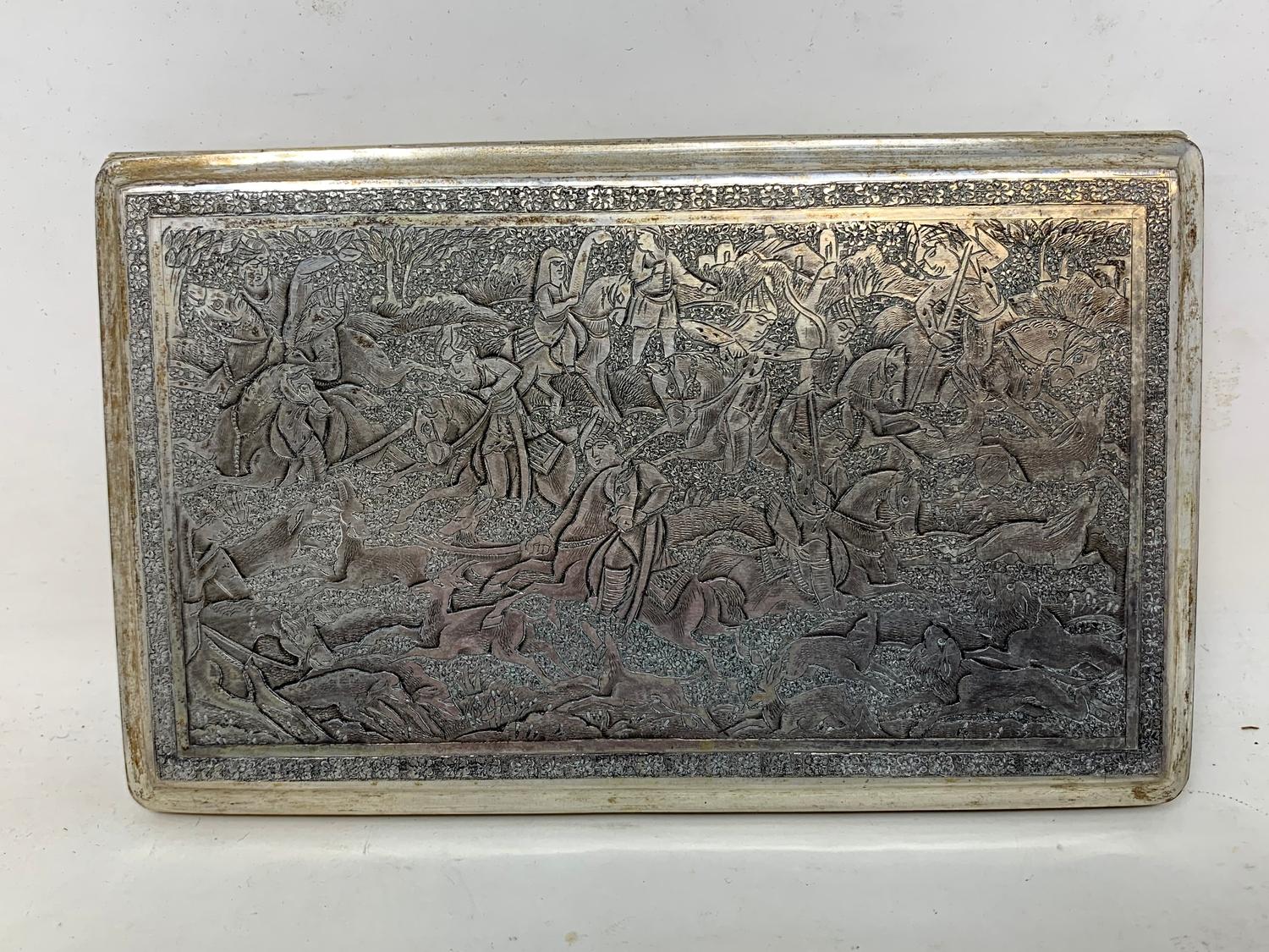 A Persian silver coloured metal cigarette case, decorated figures on horseback hunting lions and