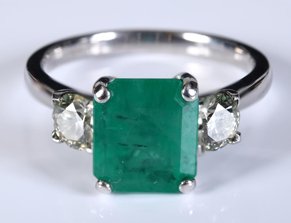 An 18ct white gold ring, set an emerald between two brilliant cut diamonds, approx. ring size M½,