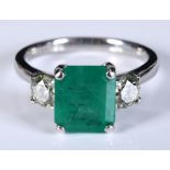 An 18ct white gold ring, set an emerald between two brilliant cut diamonds, approx. ring size M½,