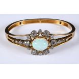 A late Victorian/Edwardian yellow coloured metal bangle, set an opal within a surround of