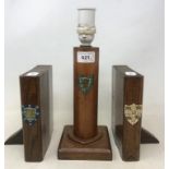 An early 20th century oak lamp base, painted with a crest, 24 cm, and a pair of similar bookends, in