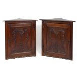 A pair of late 18th century/early 19th century French corner cupboards, the panel doors carved