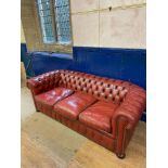 A red leather Chesterfield sofa, 200 cm wide Some ware to the leather. some claw marks probably