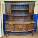 An oak dresser, top with two cupboard doors and two tier plate rack, base having two drawers and two
