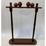 A hardwood cricket bat stand, on turned supports, to hold three bats, and with two cups for