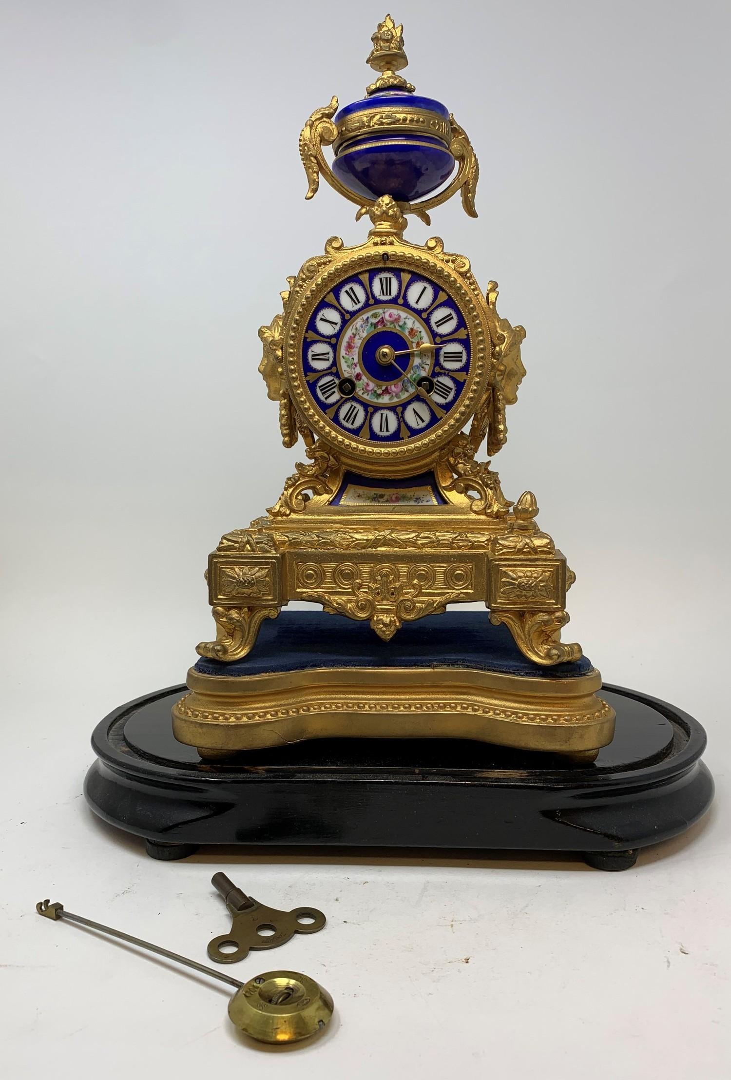 An early 20th century French mantle clock, with an 8 cm porcelain dial, decorated flowers, in a gilt