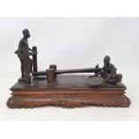 A Mg Po Kyaw, Pegu, bronze group, pounding rice, on a carved wooden base, 35 cm wide x 21 cm high