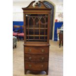 A mahogany cabinet, with astragal bar glazed doors, on a base with three bow front drawers, with