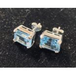 A pair of silver and emerald cut blue topaz stud earrings
