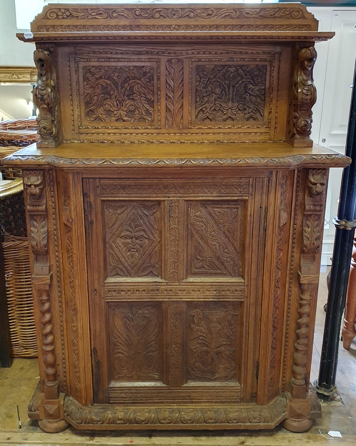 A late 19th century Anglo-Flemish oak cabinet, the raised back above a panel door, carved all over