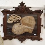A 19th century lace bonnet, in an oak frame, carved with a coat of arms, shieldguard lion rampant,