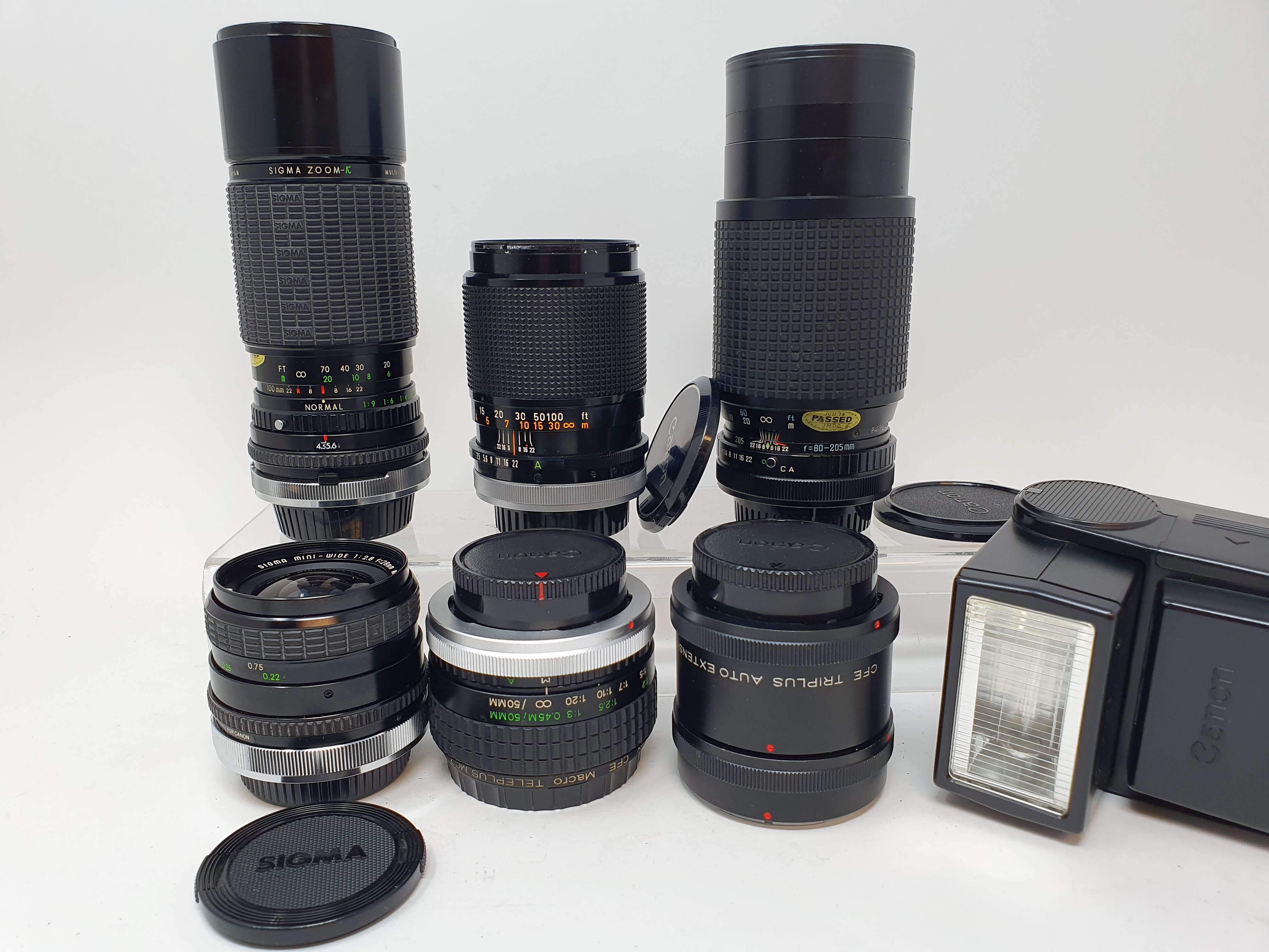 A Sigma camera lens, in outer case, another, three Canon lenses, and a Canon flash, in leather