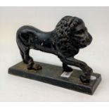 A late 19th/early 20th century cast iron door porter, in the form of a lion, the front paw on a