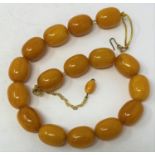 An amber bead necklace, on gold plated chain Each bead 2cm wide approx. all in weight 112.4 g