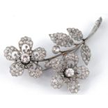 A 20th century white coloured metal and diamond floral spray brooch, decorated two flowerheads and
