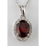 An 18ct white gold, garnet and diamond pendant, on a chain