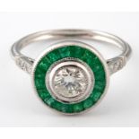 A platinum, emerald and diamond target set ring, ring size N Central diamond 0.44ct approx.
