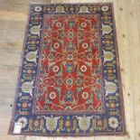 A Persian red ground rug, with main blue border, centre with repeating foliate forms, 148 x 101 cm