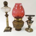 A brass oil lamp with cranberry glass shade, four other oil lamps (5)