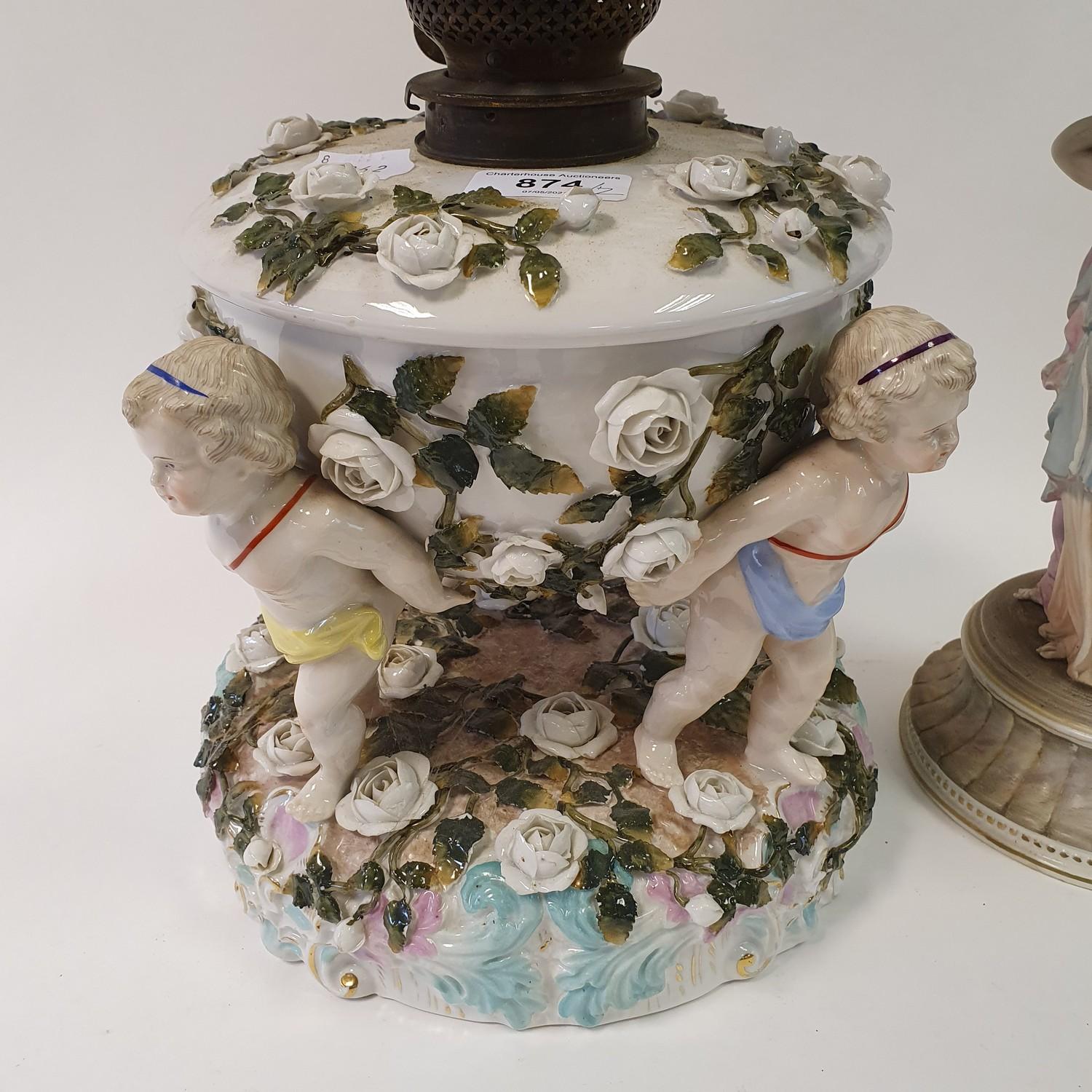 A Dresden porcelain oil lamp, flower encrusted well raised by three putti, 55 cm high, and an oil - Image 2 of 11