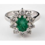 An 18ct white gold oval cut emerald and diamond cluster ring, ring size M Emerald 1.40ct, diamonds