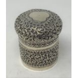 A Burmese style silver coloured metal box and cover, decorated scrolling foliage, 9.5 cm high 6.3