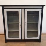 A 1920s white and black enamel cabinet, having two glazed doors, 96 cm wide