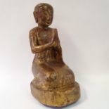An Eastern carved wood and painted figure in prayer, 53 cm high
